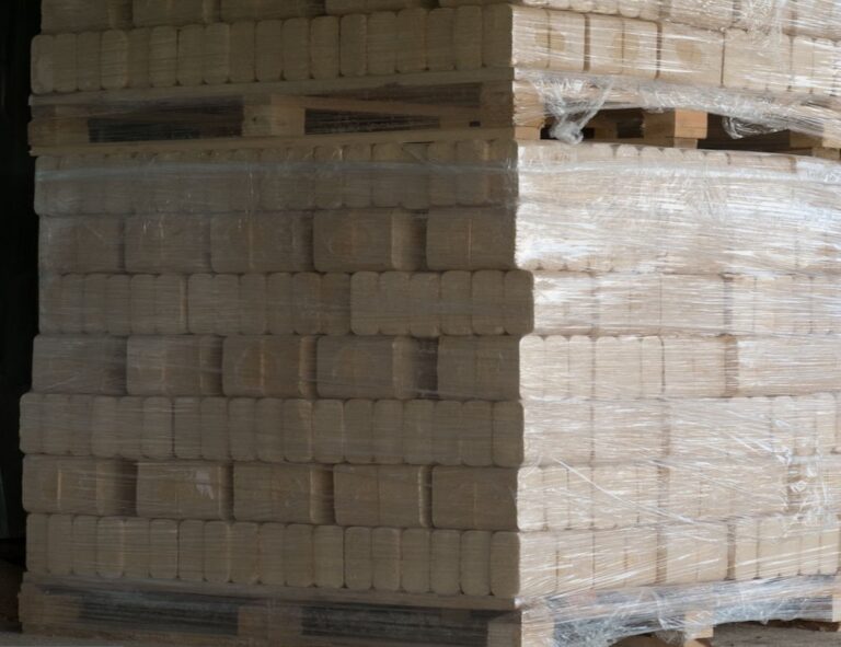 Pressed pine wood briquettes on pallets. Solid fuel for stoves from softwood shavings.