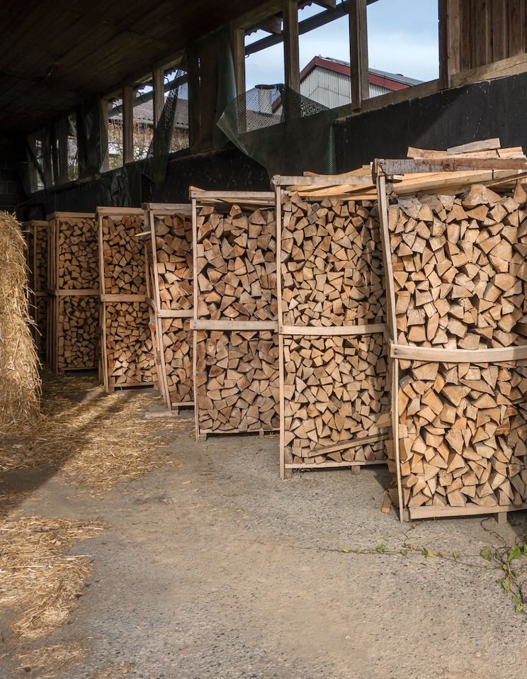 Several, diagonal one after the other positioned firewood racks in an open barn